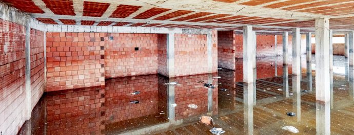 The basement of a building under construction is filled with dirty flood water