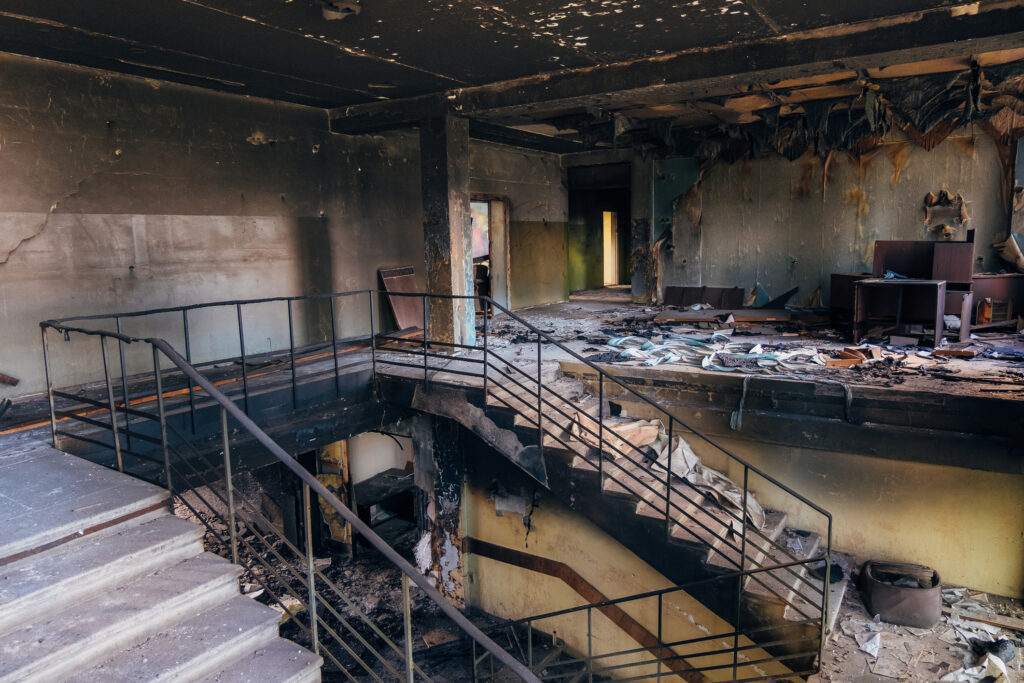 Burned interiors after fire in industrial or office building. Walls and staircase in black soot.